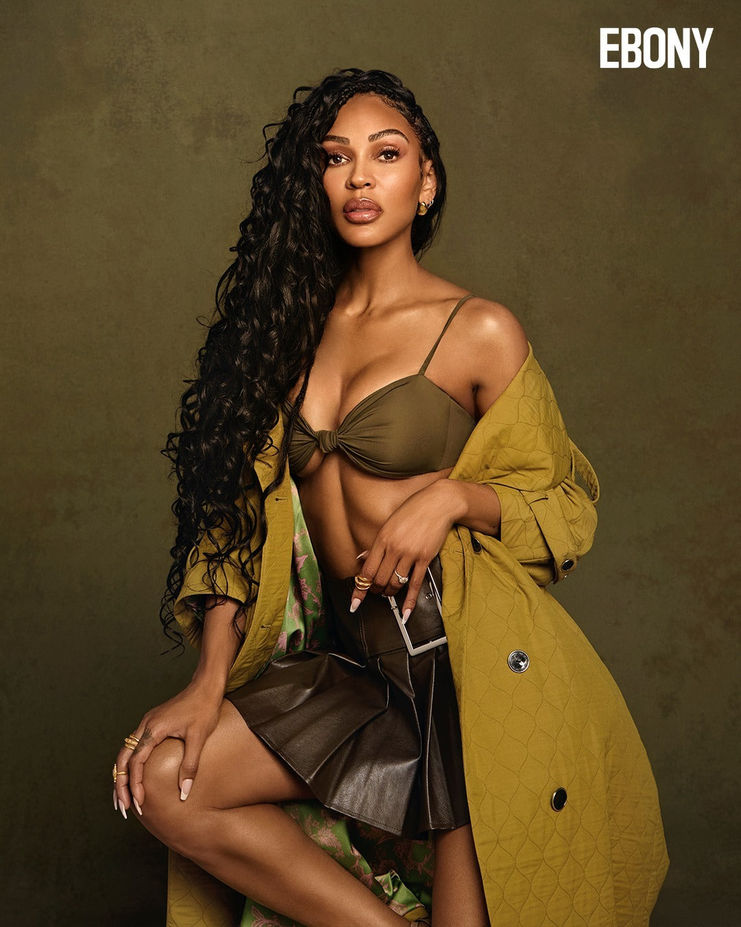 Meagan Good wearing the Palermo top in Basil with a skirt and jacket against an olive background